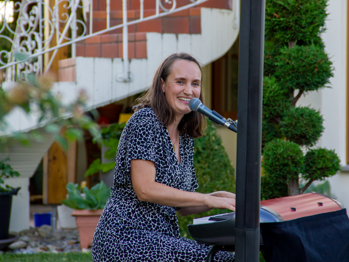 Eine Frau spielt auf dem Klavier und lächelt in die Kamera