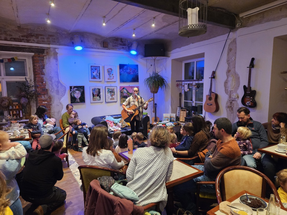 Ein Cafe mit Menschen und einer Musikerin auf der Bühne